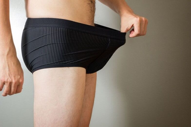 un homme baisse les yeux sur son pantalon et veut agrandir son pénis avec du soda